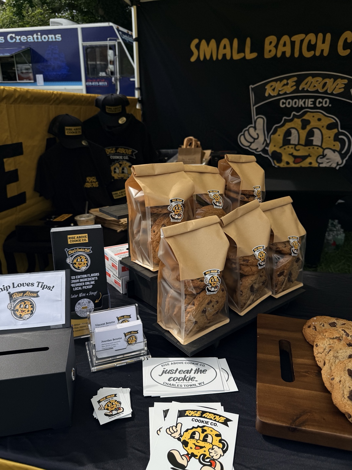 The Rise Above Cookie Co. market booth with cookies and branded merchandise